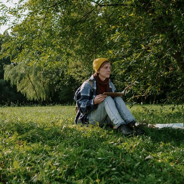 Person stretching gently in a sunny park with green grass.