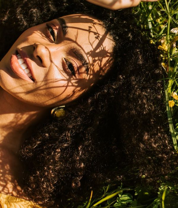 Woman in a peaceful pose in a bright, natural setting.